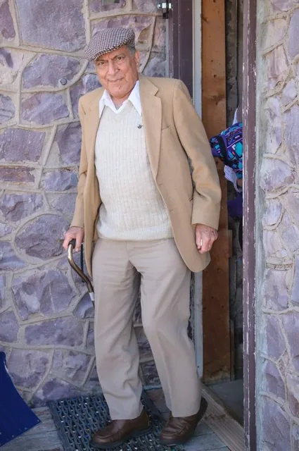 Ishwar Puri standing indoors in a light-colored suit