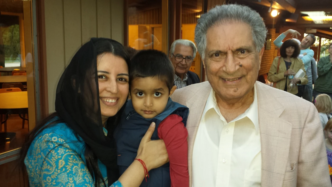 Ishwar Puri smiling beside a woman holding a young child