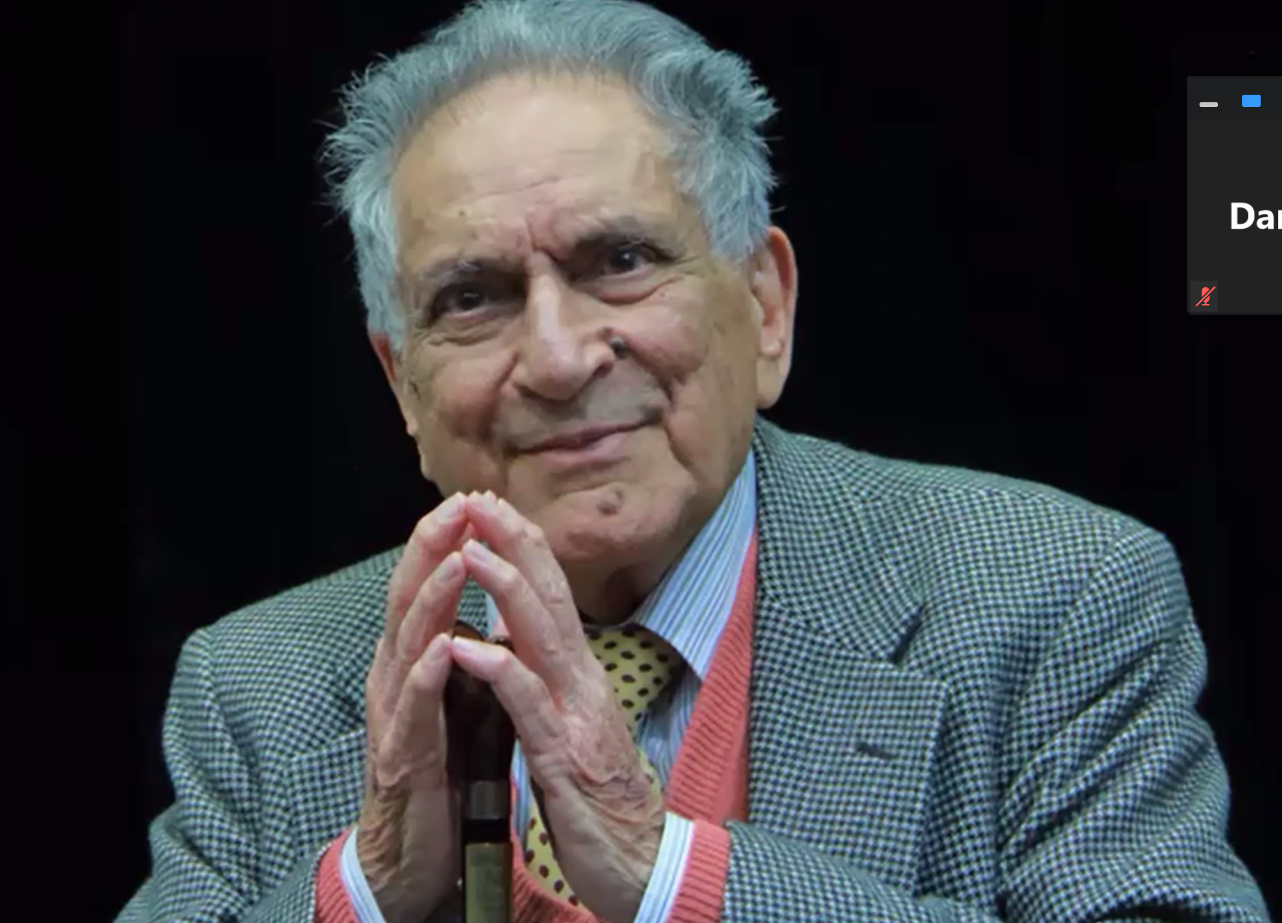 Ishwar Puri speaking on a dark stage